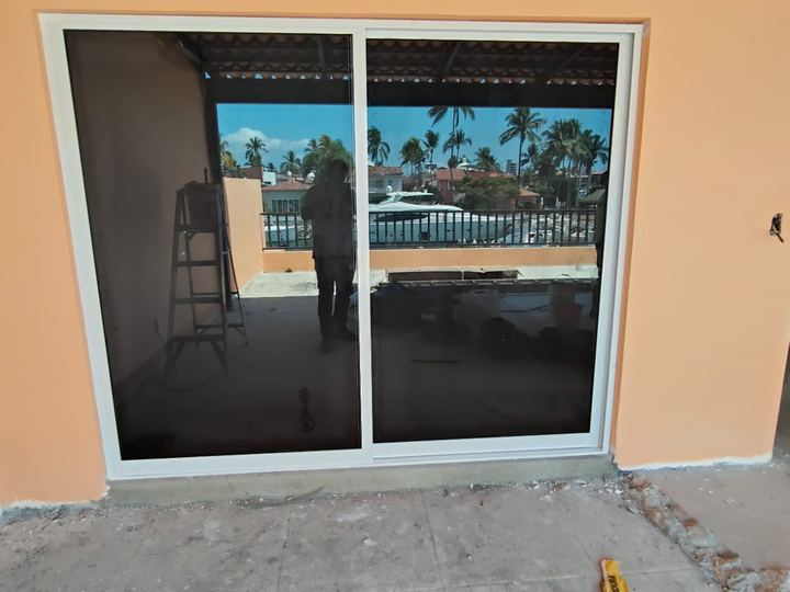 Ventana corrediza de aluminio blanco con vidrio polarizado y vista a la marina