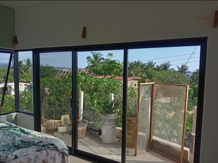 Recámara con cancelería corrediza de aluminio negro y vista al jardín