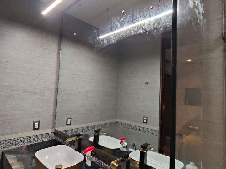 Espejo de piso a techo en baño con lavabos dorados