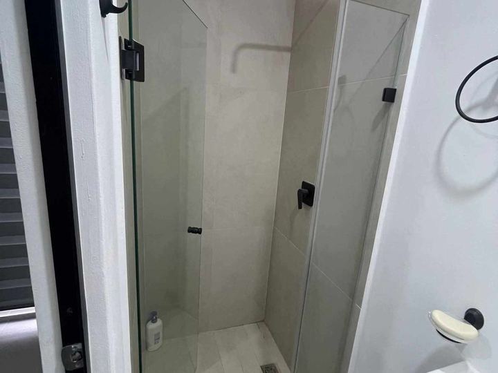 Cancel abatible con herrajes negros en baño compacto