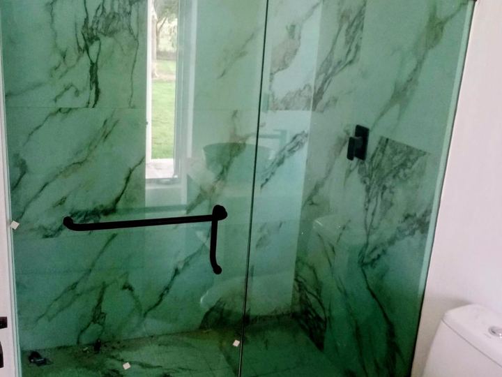 Cancel fijo con puerta sobre acabado de mármol verde