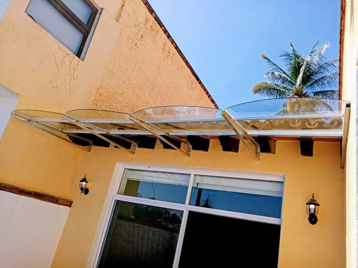 Marquesina curva de acrílico sobre ventanal